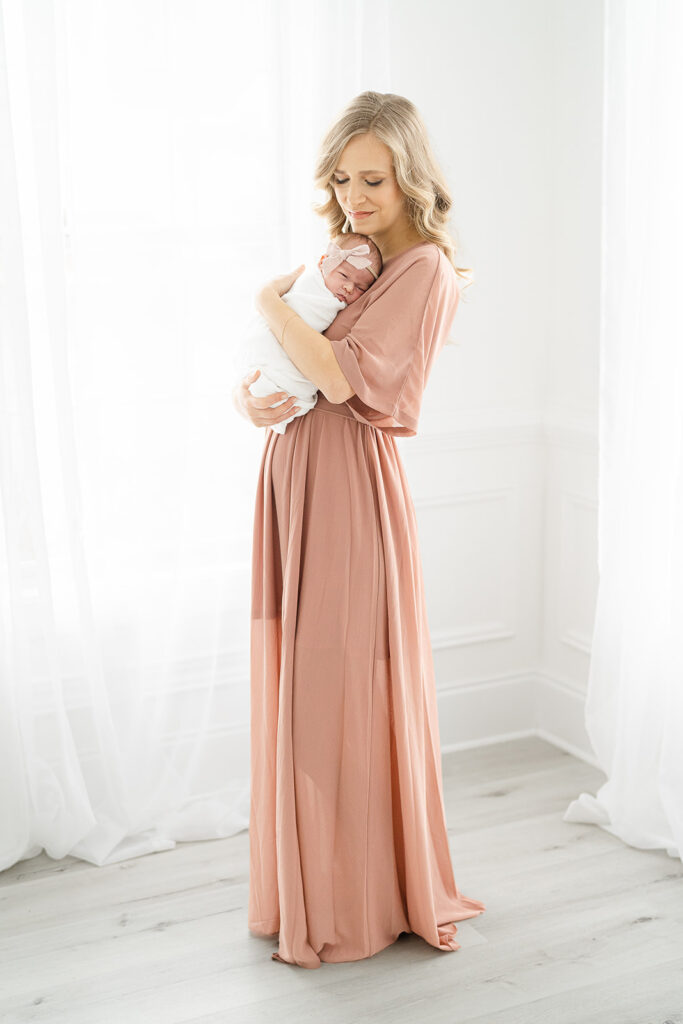 Mom holding baby in long pink dress in natural light Atlanta Newborn Photography studio
