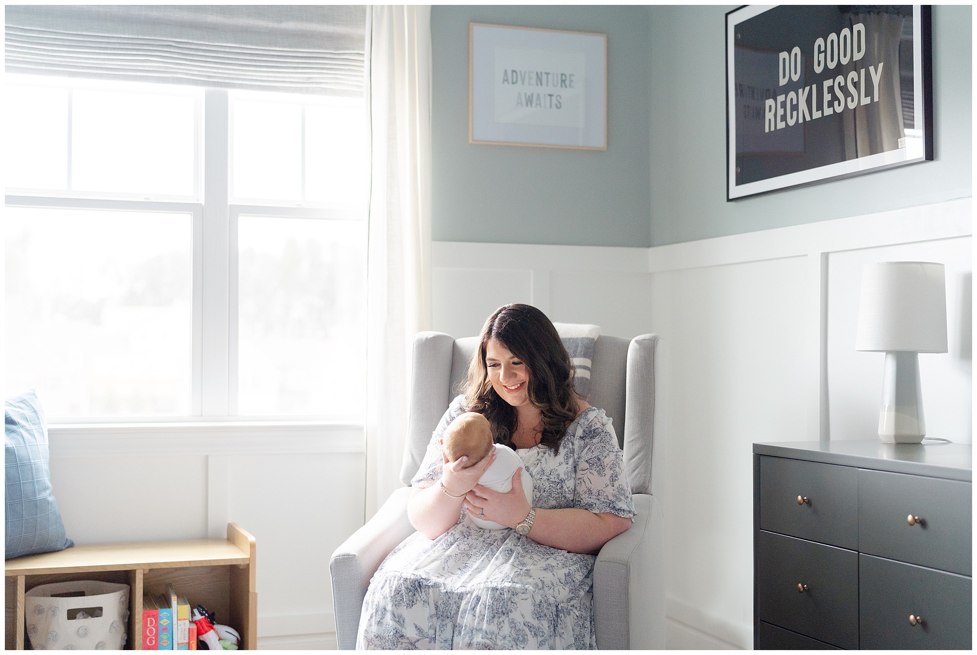 Mother sitting in nursery rocker smiling down at her baby during her Atlanta newborn session.