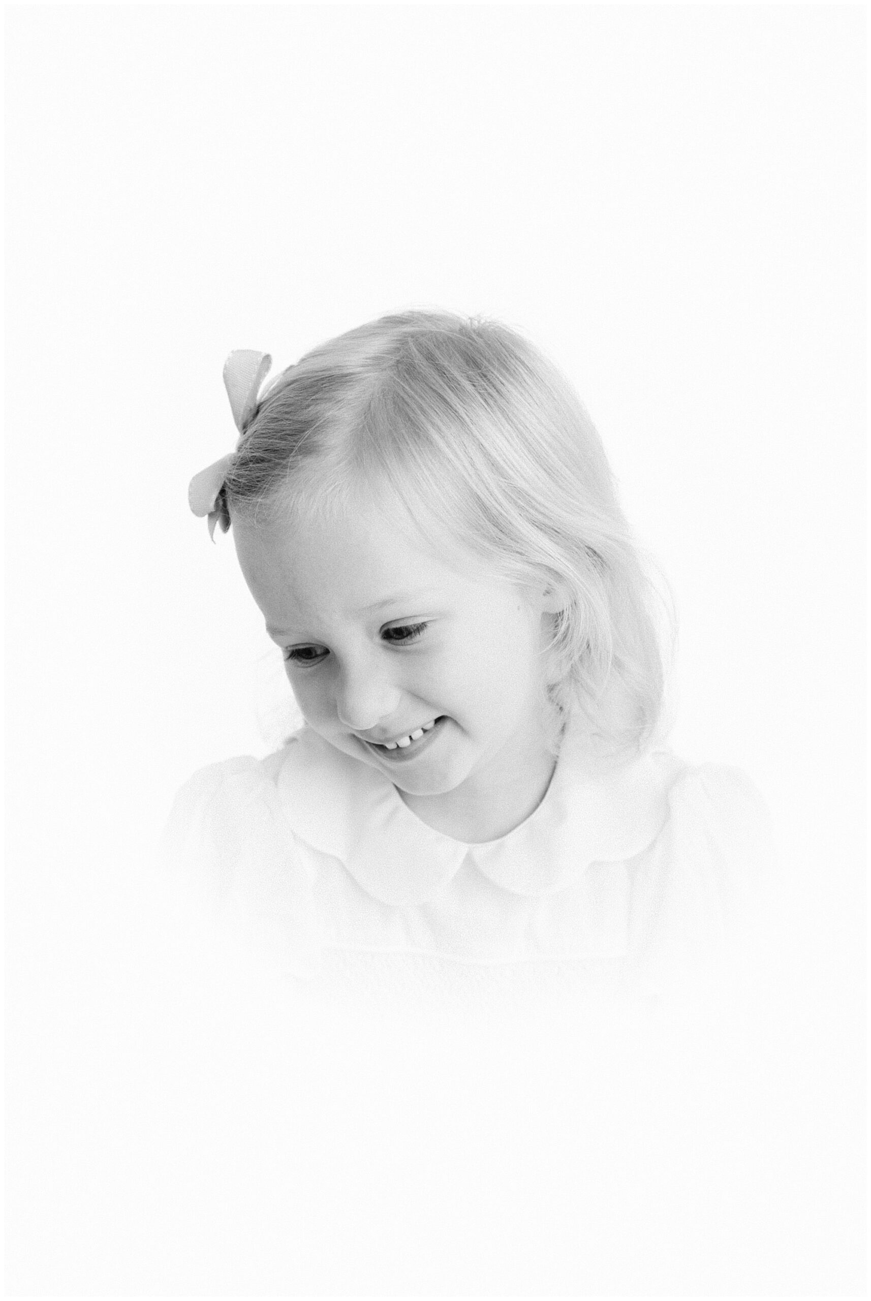 Black and white heirloom photo of a young girl smiling down.
