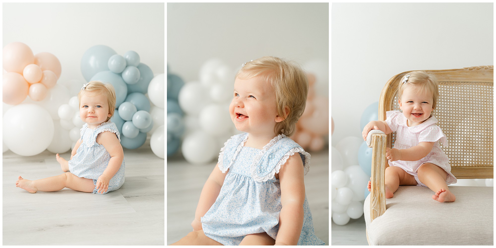 A one year old girl smiling for portraits in front of a blue, white, and pink balloon garland during her Atlanta Cake Smash session for twins.