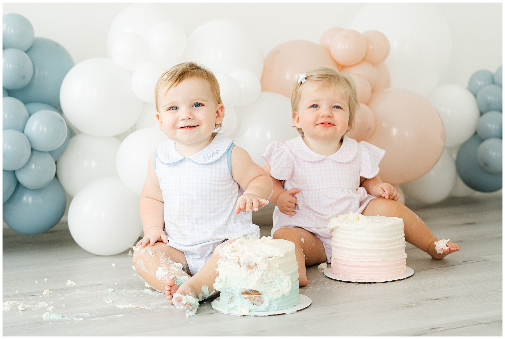 A twin boy and girl digging into cakes for an Atlanta cake smash for twins photo session.